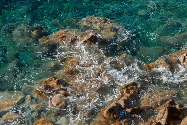 野生の岩のビーチの海岸線や海 波の海の海岸線 穏やかな海の岩の上に飛び出す 白い海の泡と小さな泡 トップビューを作成する海岸の岩に波を破る — ストック写真