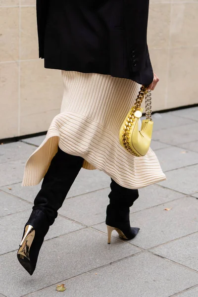 stock image Paris, France - October, 3, 2022: woman wears wrap front ribbed cotton jersey dress, black suede pointed heels knees boots, high boots, gold chain handbag from Stella McCartney, street style details.