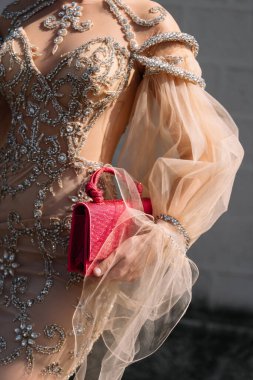 Milan, İtalya - 22 Eylül 2022: Bej tül işlemeli, uzun bir kokteyl elbisesi ve Zara 'dan gelen neon pembe elmaslı el çantası giyen kadın..