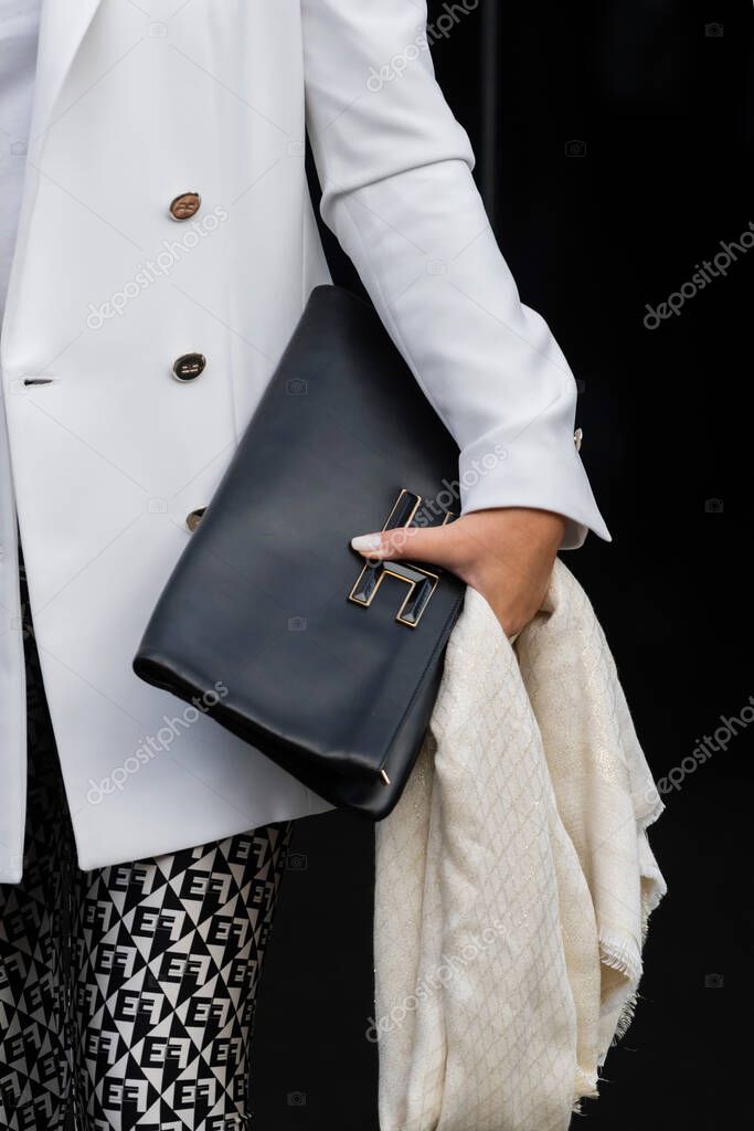 Milan, Italy - September, 25: woman influencer wearing maxi rectangular clutch bag with gold logo from Elisabetta Franchi. Fashion blogger outfit details, street style.