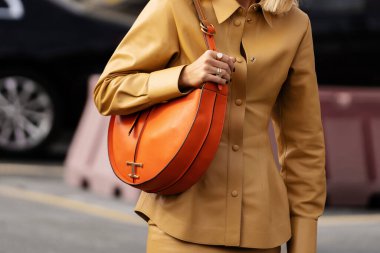 Milan, İtalya - 23 Eylül: açık kahverengi deri ceket giyen, üzerinde Tods Tods Tods 'un altın logosu olan turuncu zamansız berduş omuz çantası olan kadın nüfuzu. Moda blogcusu kıyafet detayları, sokak tarzı.