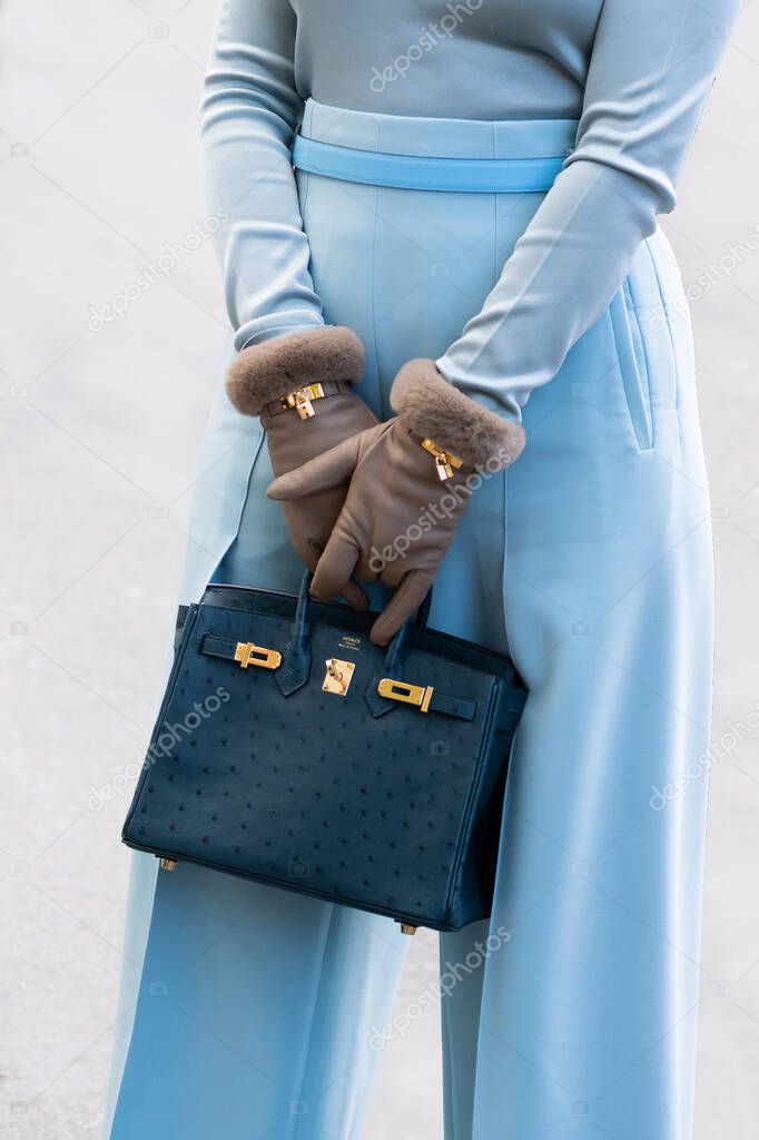 Paris, France - October, 1: woman wearing navy blue ostrich leather Birkin handbag from Hermes, street style outfit details.