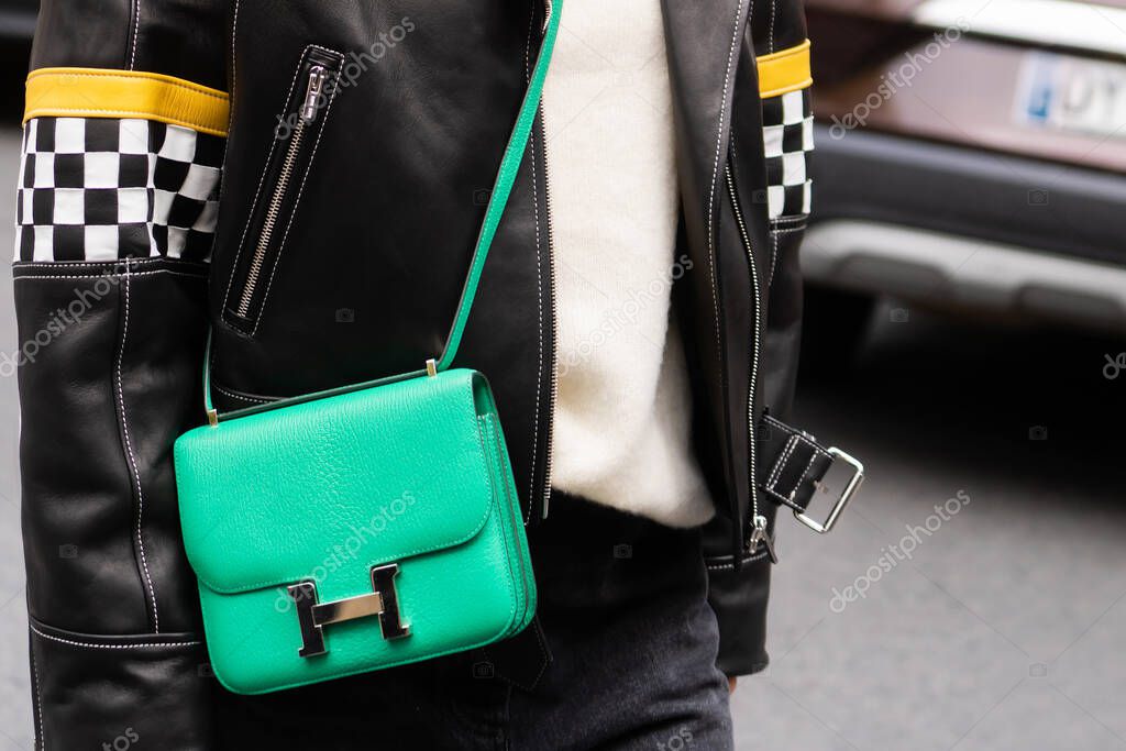 Paris, France - October, 1, 2022: woman wearing Constance green leather bag from Hermes, street style outfit details.