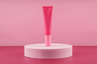 Podyum kaidesinde pembe kozmetik ürünü. Pembe arka planda yüz kremi modeli, kadın derisi için losyon. Güzellik nemlendirici ambalaj. Losyon sunumu modeli.