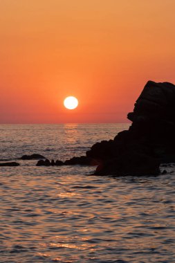 Beautiful view of orange sunset with rocks in Calabria, Mediterranean Sea, Italy. Tropical colorful sunrise landscape. Seascape