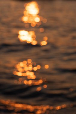 Awe beautiful vibrant orange shallow sun path of round highlights spot particles on sea out of focus area. Summer travel scene
