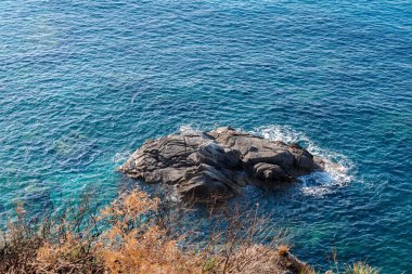 Kayalık sahillerde dalgalar, deniz kıyıları büyük kayaların üzerinde dalgalar eziliyor, yaz güneşli bir gün.