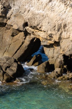 Kayalık sahillerde dalgalar, deniz kıyıları büyük kayaların üzerinde dalgalar eziliyor, yaz güneşli bir gün.