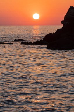 Beautiful view of orange sunset seascape with rocks in Italy. Tropical colorful sunrise landscape