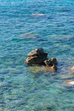 Kayalık sahillerde dalgalar, deniz kıyıları büyük kayaların üzerinde dalgalar eziliyor, yaz güneşli bir gün.