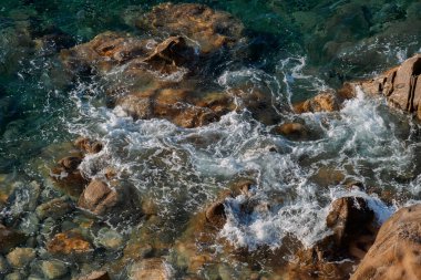 Kayalık sahillerde dalgalar, deniz kıyıları büyük kayaların üzerinde dalgalar eziliyor, yaz güneşli bir gün.