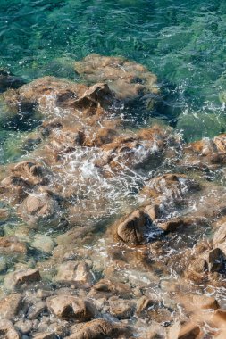 Kayalık sahillerde dalgalar, deniz kıyıları büyük kayaların üzerinde dalgalar eziliyor, yaz güneşli bir gün.