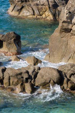 Kayalık sahillerde dalgalar, deniz kıyıları büyük kayaların üzerinde dalgalar eziliyor, yaz güneşli bir gün.