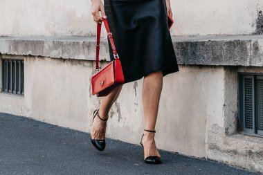 Milan, İtalya - 19 Haziran 2022: Kadın Prada 'dan yüksek topuklu ayakkabı giyiyor ve plaka takıyor. Kırmızı, sokak tarzı aksesuarlarla..