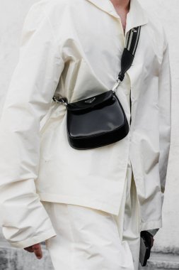 Milan, İtalya - 19 Haziran 2022: Adam siyah Prada Cleo mini fırçalı deri çanta giyiyor, sokak tarzı aksesuarlar..