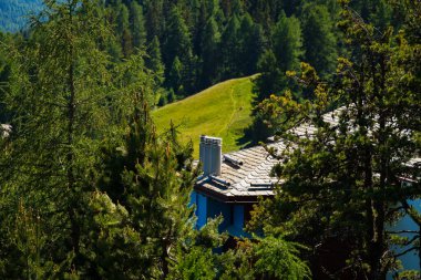 İsviçre, St.Moritz - 6 Haziran 2023: binalar, tepeler ve ağaçlar, özel evler, kulübeler ve dağlarla dolu şehir manzarası.