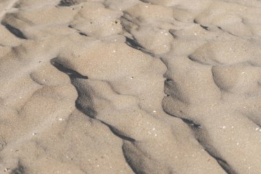 Sahilde kum, arka plan olarak. Üst manzara, yazın kumsalın kum desenine yakın çekim.