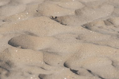 Sahilde kum, arka plan olarak. Üst manzara, yazın kumsalın kum desenine yakın çekim.