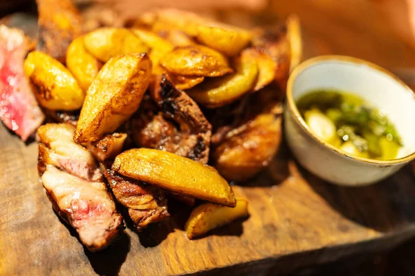 Baked potato wedges with steak and sauce on wooden desk, dish in restaurant