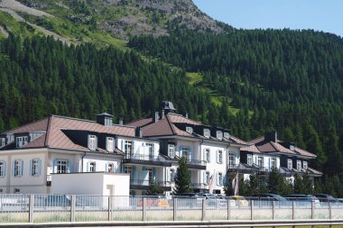 İsviçre, St.Moritz - 6 Haziran 2023: binalar, tepeler ve ağaçlar, özel evler, kulübeler ve dağlarla dolu şehir manzarası.