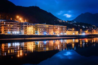 Lecco 'nun gece manzarası. Şehir ışıklarının suya yansıması. Como Gölü