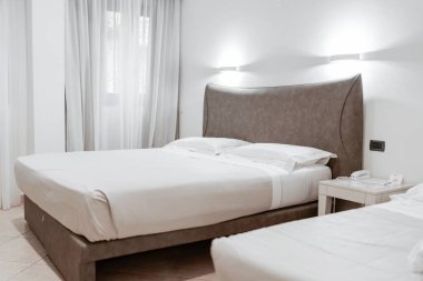 Lüks otel odasında beyaz şilteli en az çift kişilik yatak. Rahat bir yatak ve yastıklar..
