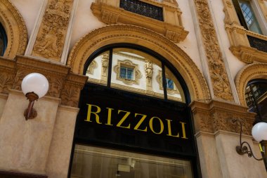 Milan, Italy - 24.04.2024: Rizzoli showcase located at shopping gallery in the center of Milan, Galleria Vittorio Emanuele, vitrine of the clothes shop clipart