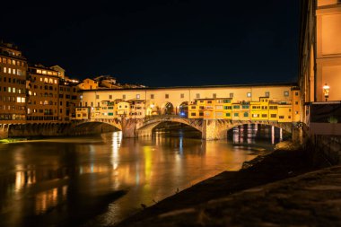 Floransa, İtalya - 31 Ağustos 2022: Ponte vecchio gece Floransa 'sında Arno Nehri üzerinde sıcak bir şekilde parlıyordu.