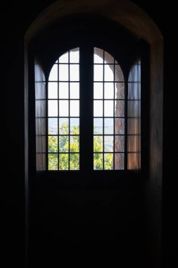 Gradara, İtalya - 25 Ağustos 2022: Gradara Şatosu 'nun kavisli penceresinden dışarıdaki parlak manzarayı karanlık iç kısımlara karşı görüntülemek