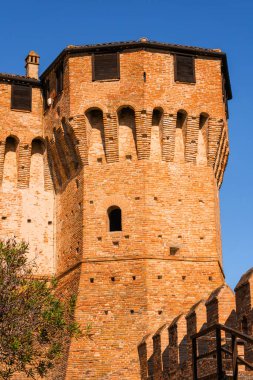 Gradara, İtalya - 25 Ağustos 2022: Gradara Kalesi 'ndeki tuğla kuleye yakından bakın, mimari detaylar ve mavi gökyüzü arkaplanı sergileniyor