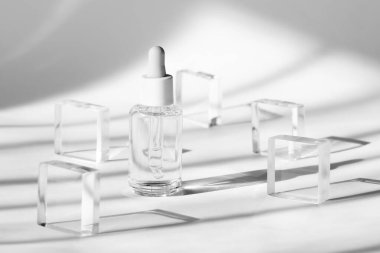 Serum cosmetic bottle mockup on acrylic transparent solid block pedestal on white background, shadow from sun, natural light from windows. Geometric stand, podium for cosmetics, product presentation clipart