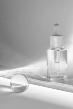 berrak serum şişesi ve kristal küre beyaz arka plan, kozmetik ürün paketi üzerine ışık yansımaları