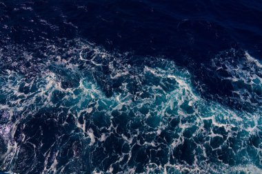 Karanlık okyanus dalgaları ve parlak beyaz deniz köpüğü arasındaki zıtlığı yakalayan hava görüntüsü dinamik ve dramatik deniz manzarası yaratır. Arkaplan veya deniz temaları
