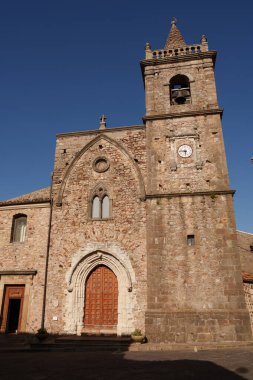 A historic Gothic-style stone church with a prominent bell tower in a Mediterranean village, showcasing intricate architecture and ancient cultural heritage in a serene setting clipart