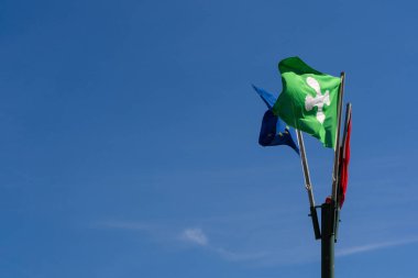 Lombardia ve Avrupa Birliği 'nin bölgesel bayrakları açık mavi gökyüzüne karşı dalgalanıyor, bölgesel kimlik ve birliği simgeliyor