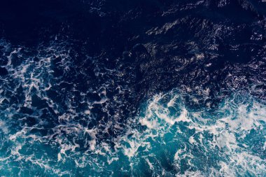 Karanlık okyanus dalgaları ve parlak beyaz deniz köpüğü arasındaki zıtlığı yakalayan hava görüntüsü dinamik ve dramatik deniz manzarası yaratır. Arkaplan veya deniz temaları