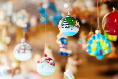 Elle boyanmış Noel süslemeleri, mücevherler ve biblolar da dahil olmak üzere, sıcak ışıklarla güzelce aydınlatılan festival pazar ortamındaki iplere asılıyor.