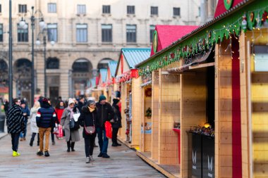 Milano, İtalya - 18.12.2022: İnsanlar şehir merkezinde mevsimsel alışveriş deneyimleri olan bayram marketlerinde sıra sıra yürüyorlar. Sahne, tarihi mimari ve tatil atmosferine karşıdır..