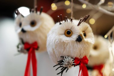 Dallı el yapımı baykuş süsü, kırmızı fiyonk ve şenlikli detaylar. Yumuşak ışıklandırma ve bulanık arkaplan tatil dekorunu ve işçiliğini vurguluyor