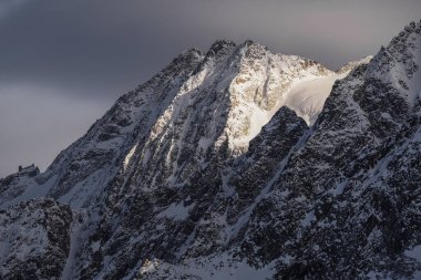 Passo Tonale yakınlarındaki dağların panoramik manzarası, Ponte di Legno, İtalya. Gri bulutlu gökyüzünün altında büyük karlı dağ sıraları. Güneşli bir günde kayak merkezi manzarası. Dağ kayak merkezi. Kar yamacı