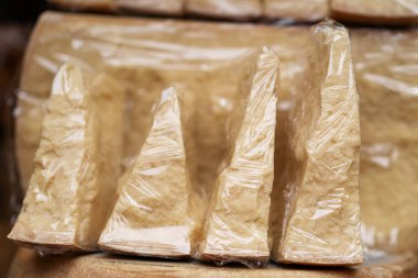 Pazar vitrininde tek tek paketlenmiş parmesan peyniri parçacıklarının yakın plan çekimleri, doku ve zanaat kalitesini ön plana çıkarıyor