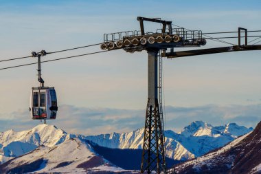 Piani di Bobbio, İtalya - 24.12.2022: Kablo araç çelik destek kulesinin yanından geçiyor. Kışın kayak merkezinde kayak yapan insanlar. Tatiller, kar giysileri kiralama, kayak, snowboard ve dağ manzarası konsepti