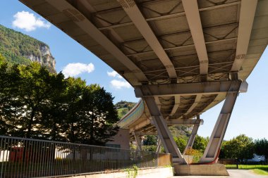 Görünür destek kirişleriyle büyük köprünün altından görüntüyü al. Sahne, kentsel altyapıyla çevredeki doğal ortamı harmanlıyor.
