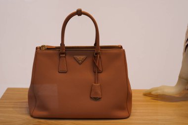 Milan, İtalya - 24.04.2024: Ahşap yüzeyde gösterilen zarif kahverengi Prada çanta, çanta vitrini.