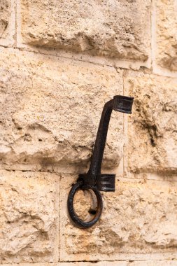 Metal kancalar desenli taş duvara karşı hizalanmış, kırsal tasarım ve işçilik sergiliyor.