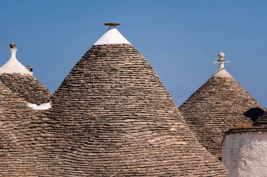 İtalya 'nın Alberobello kentinin dar sokaklarında taştan yapılmış üç adet sivri çatılı bina, konik çatılı ikonik Trulli evleri, UNESCO Dünya Mirası sahası