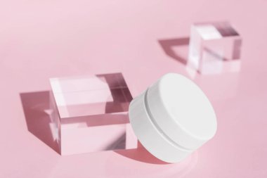 Acrylic Block 'ta Firming Cream Jar modeli, yumuşak pembe arka plan, temiz ve minimalist güzellik ürünü tasarımı