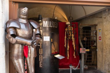 San Gimignano, İtalya - 01.05.2021: Kafeste ortaçağ zırhı ve iskeleti bulunan müze girişi, tarihi işkence aletleri sergileniyor