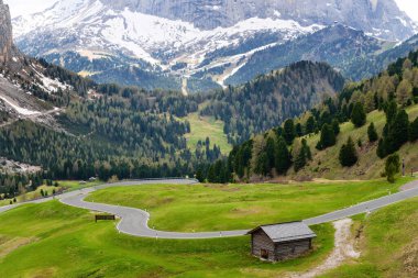 Dolomites, İtalya 'daki Funes Vadisi yakınlarındaki verimli yeşillikler arasında dolambaçlı yolu ve kulübesi olan huzurlu dağ manzarası..