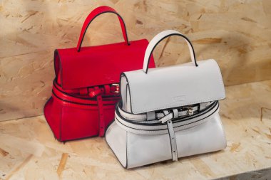 Milan, İtalya - 12 Nisan 2025: Moschino mini çantaları ahşap arka planda kırmızı ve beyaz deri. Ön manzara, perakende satış yapan moda aksesuarları.